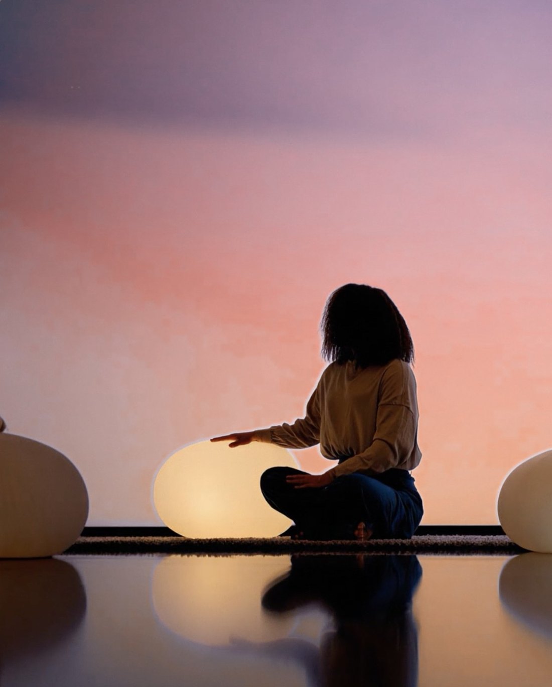A woman sits beside a glowing orb, hand resting on it